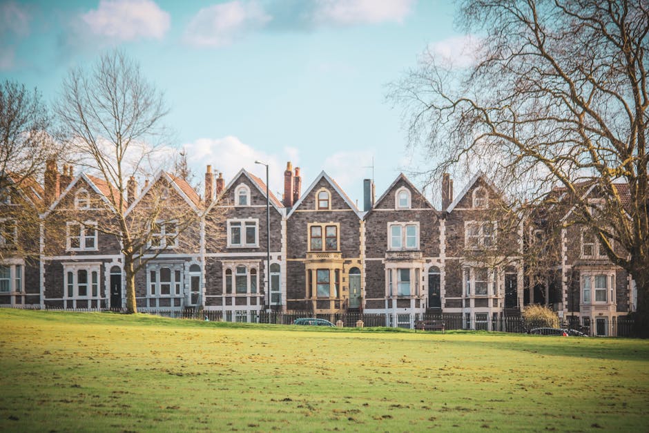 A panoramic view of a residential area in Kingston with numerous terraced and semi-detached houses featuring brown, grey, and white facades, many with pitched roofs and chimneys. Some houses have dorm
